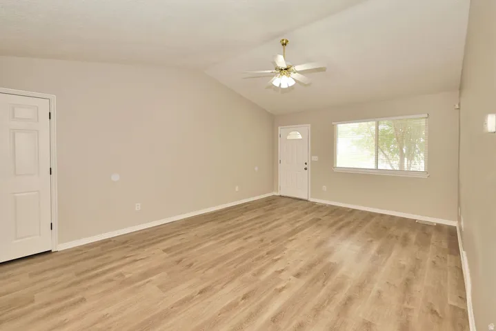 Spacious interior featuring wood-finish flooring, vaulted ceilings, and neutral wall tones