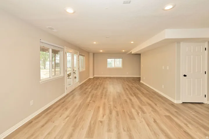 Spacious lower-level area featuring wood-finish flooring, recessed lighting, and neutral wall tones