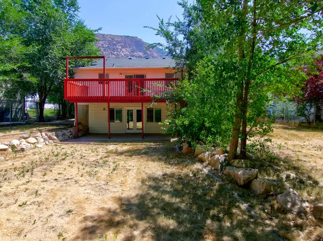 Two-story exterior with a vibrant red deck and a lower-level patio