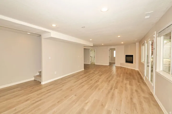 Spacious finished room featuring wood-finish flooring, recessed lighting, and a corner fireplace