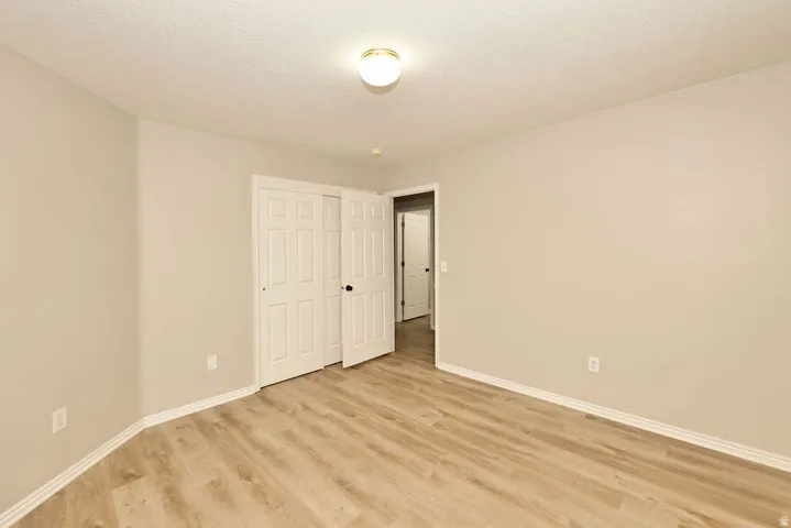 Interior room featuring wood-finish flooring, light-toned walls, white baseboards, and a semi-flush ceiling light fixture