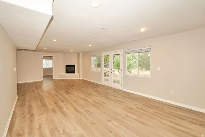 Spacious interior featuring wood-finish flooring, a contemporary fireplace, and recessed lighting