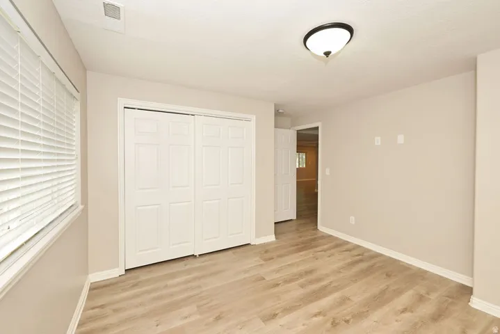 Bedroom with wood-finish flooring, neutral wall paint, and white baseboards