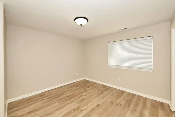 Room featuring wood-finish flooring, neutral wall paint, and white baseboards