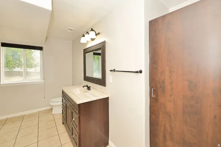 Bathroom featuring a single vanity with dark wood-finish cabinetry, a light-toned countertop, and a recessed sink with a matte black faucet