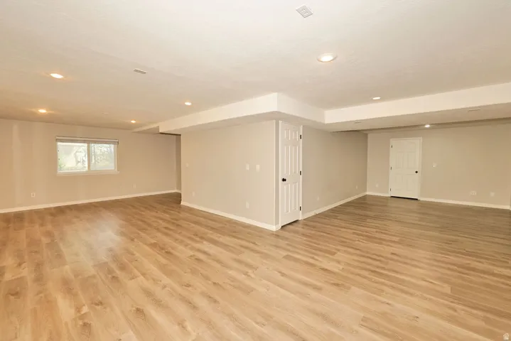 Spacious room featuring wood-finish flooring, recessed lighting, neutral wall paint, white trim, and white paneled doors