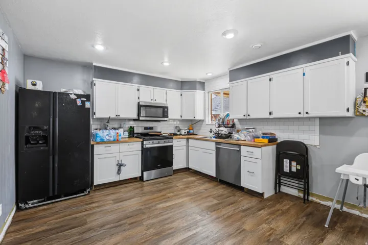 Kitchen featuring wood-finish flooring, white cabinetry with dark hardware, a white subway tile backsplash, and recessed lighting