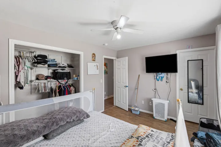 Bedroom featuring wood-finish flooring, a ceiling fan, and a built-in closet system with shelving and hanging rods