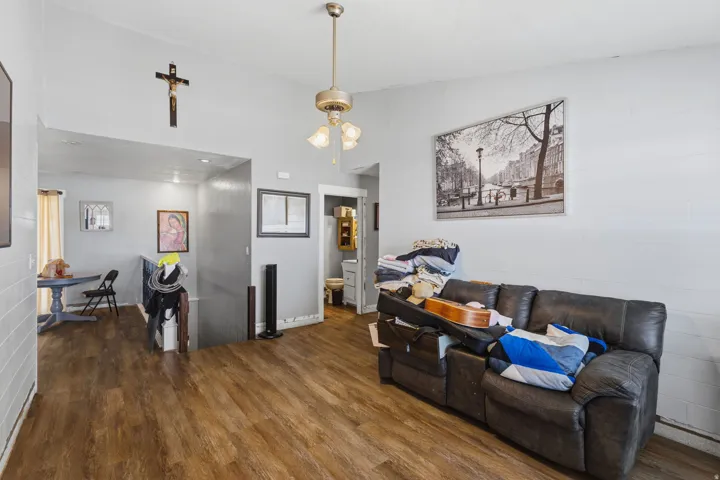 Spacious living area featuring wood-finish flooring, light gray walls, a ceiling-mounted light fixture, and an open entryway to a lower level