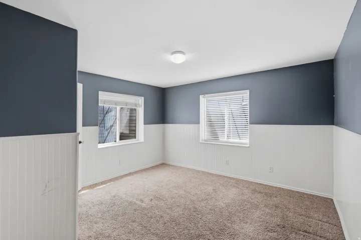 Carpeted room with two windows featuring horizontal blinds