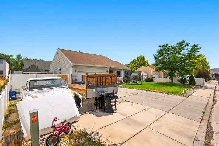 Rear exterior featuring a two-car garage, an elevated wooden deck, and a white privacy fence