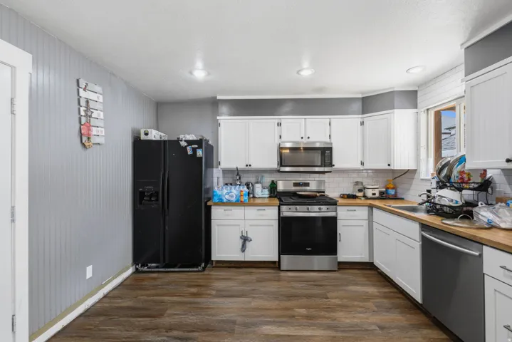 Kitchen featuring white cabinetry, stainless steel appliances, wood-finish flooring, recessed lighting, and a white subway tile backsplash