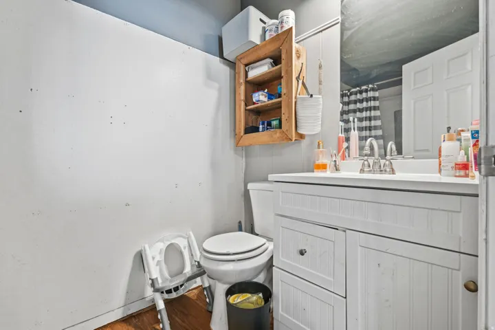Bathroom featuring a white vanity with beadboard detailing, a white countertop with an integrated sink, and a wooden wall-mounted cabinet