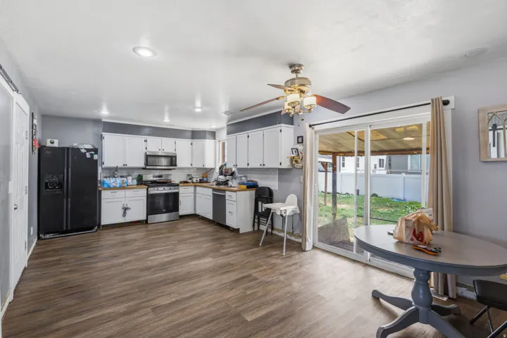Kitchen and dining area featuring wood-finish flooring, white cabinetry, recessed lighting, and a ceiling fan