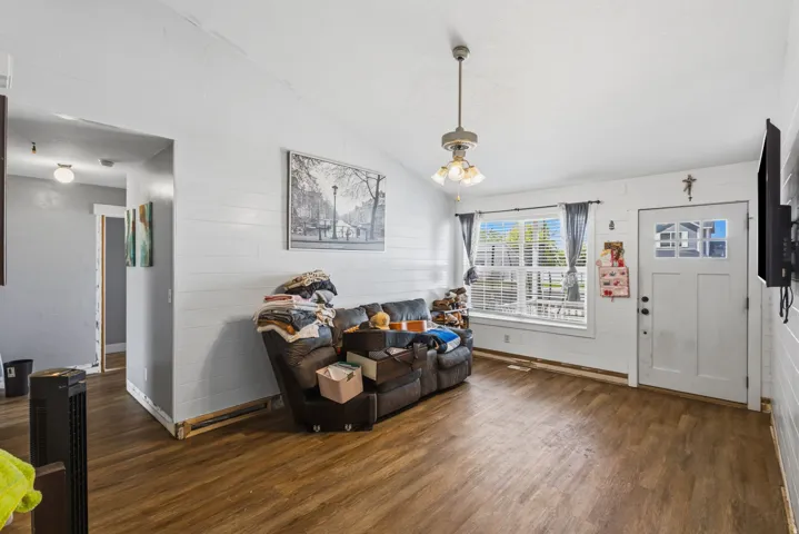 Living area featuring wood-finish flooring, white shiplap walls, and a vaulted ceiling
