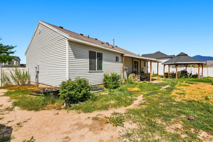 Spacious rear yard with a covered patio, a separate gazebo structure, and a perimeter fence