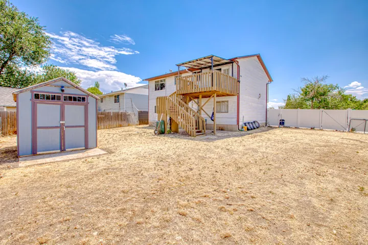 Spacious backyard featuring a two-story residence with an elevated wood deck and staircase