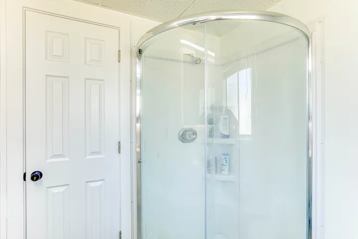 Curved glass shower enclosure with chrome-finish hardware and integrated shelving