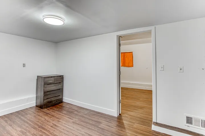 Room featuring wood-finish flooring, white painted walls, and a contemporary ceiling light fixture