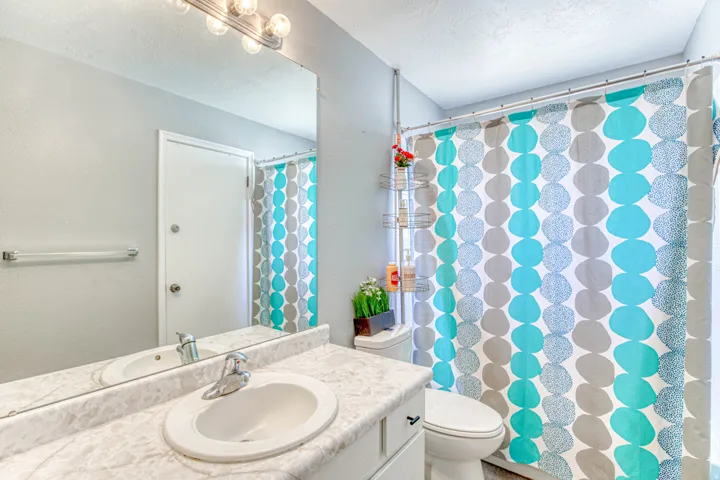 Bathroom featuring a single vanity with an integrated sink, a large wall-mounted mirror, and a multi-bulb vanity light fixture