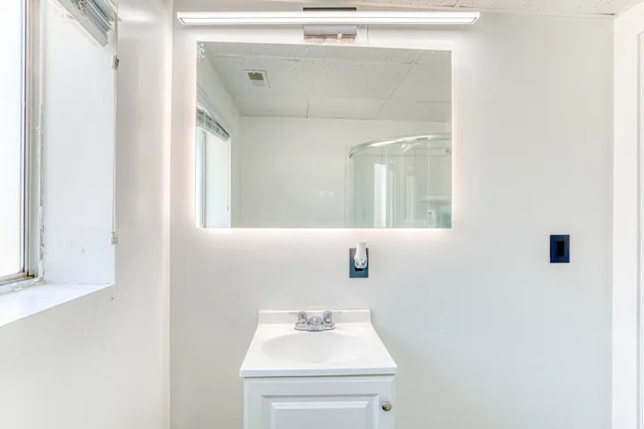 Bathroom vanity featuring a single basin sink, white cabinetry, and a countertop