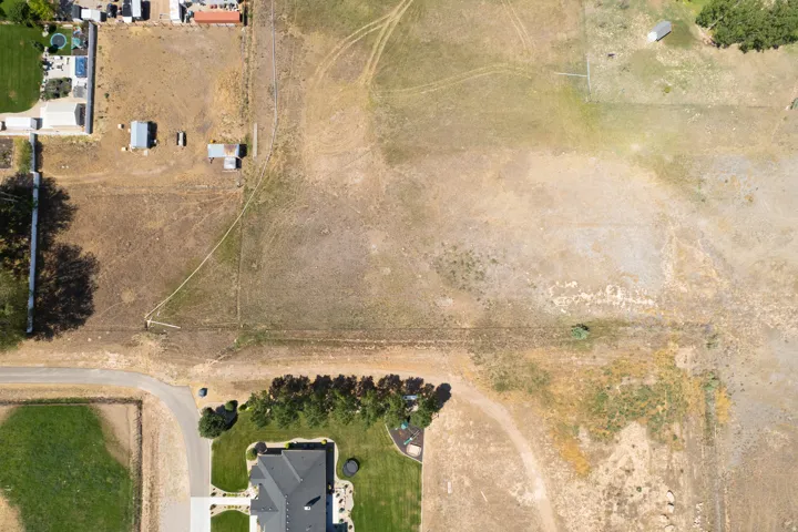 Expansive parcel featuring dry grass and visible property lines, with a paved road bordering one side