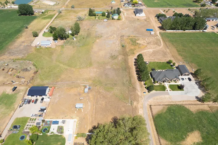 Expansive rural property featuring an established residence, detached garage, manicured lawn, paved driveway, and mature trees