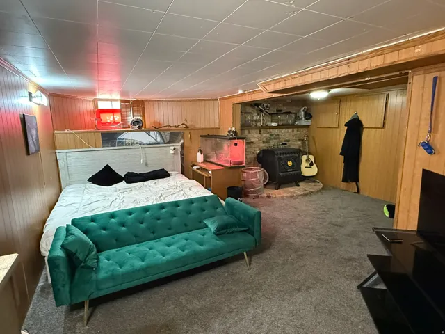Carpeted room featuring wood-paneled walls and a drop ceiling
