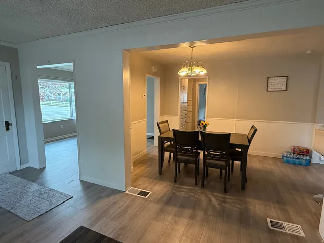 Dining area featuring wood-finish flooring, wainscoting, and a central chandelier