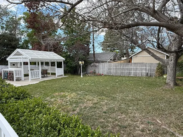 Expansive yard featuring a white gazebo with an attached bar and seating area