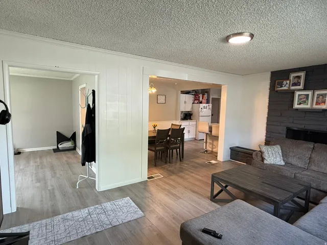 Open-concept living area featuring wood-finish flooring, a stone-faced fireplace, and recessed lighting