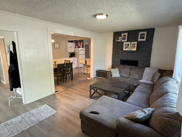 Living area with wood-finish flooring, a dark stone-clad fireplace, and recessed lighting