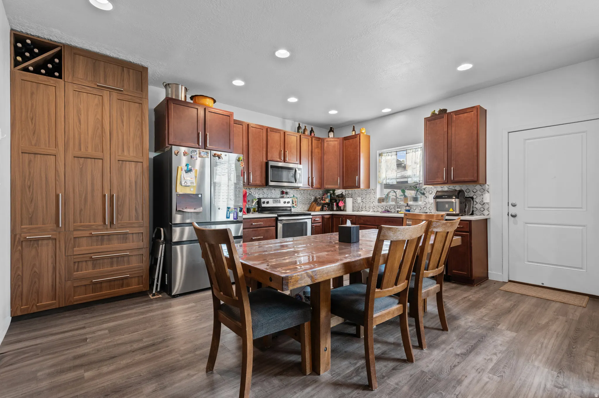 Open-concept kitchen featuring wood-finish flooring, recessed lighting, and a window above the sink
