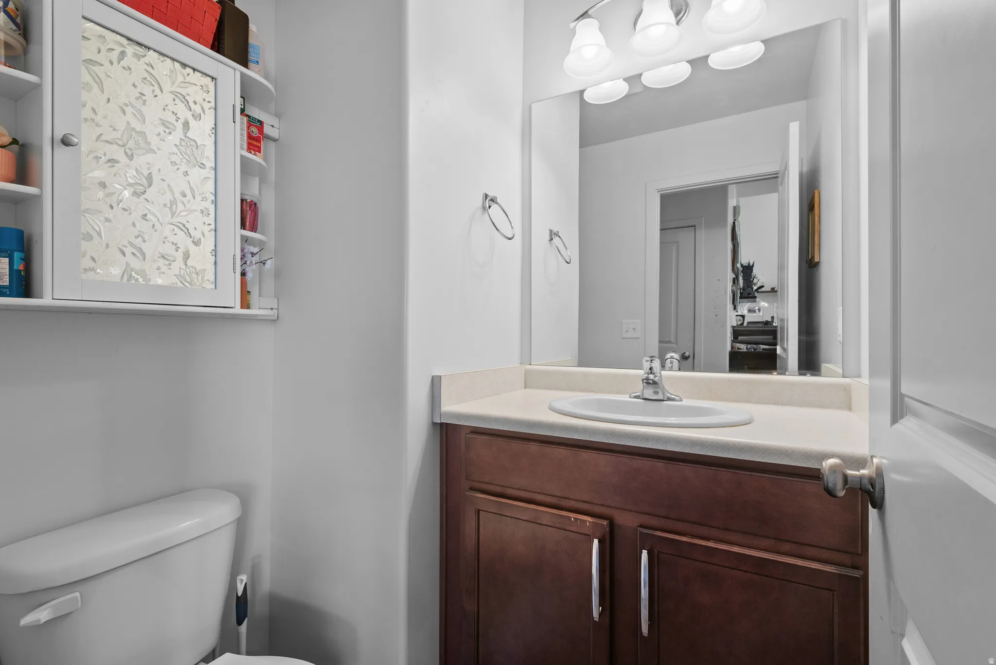 Bathroom vanity with wood-finish cabinetry, light-toned countertop, and integrated sink