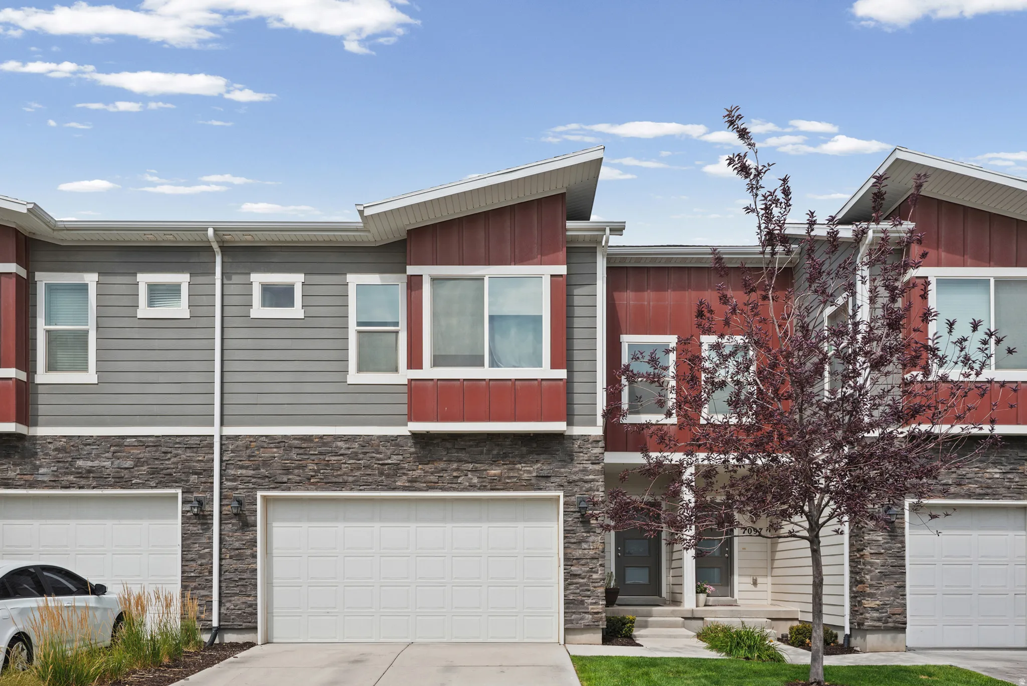 Modern townhome exterior featuring red vertical siding accents and gray horizontal siding