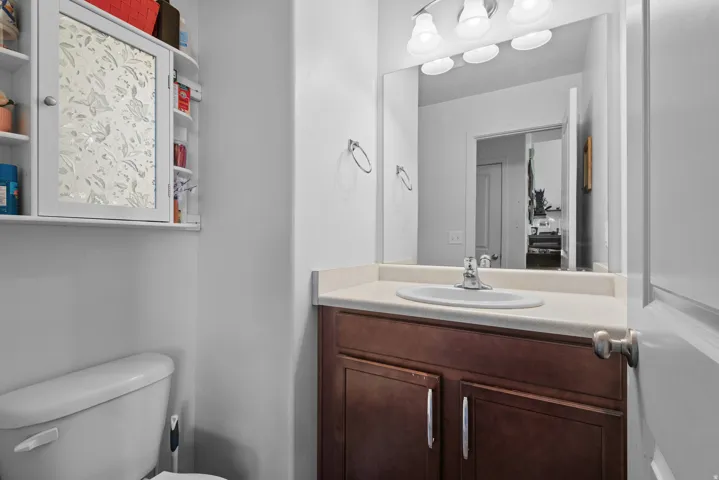 Bathroom vanity with wood-finish cabinetry, light-toned countertop, and integrated sink