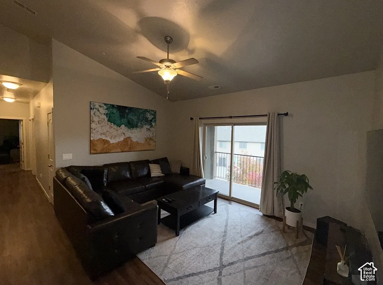 Vaulted ceilings, wood-finish flooring, ceiling fan, and a sliding glass door with a metal-railing balcony