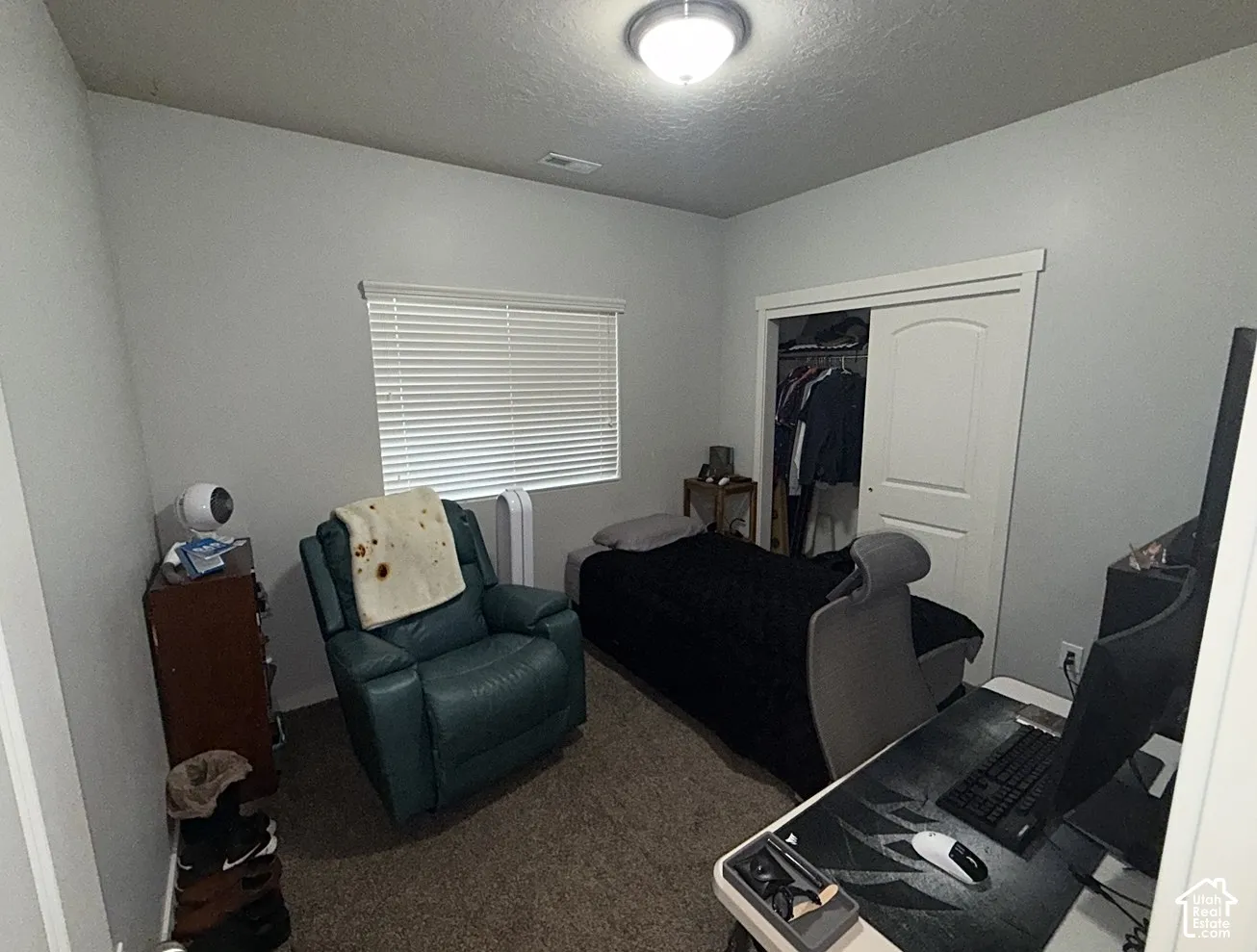 Neutral-toned interior room featuring wall-to-wall carpeting, a horizontal window with blinds, and a built-in closet with sliding paneled doors