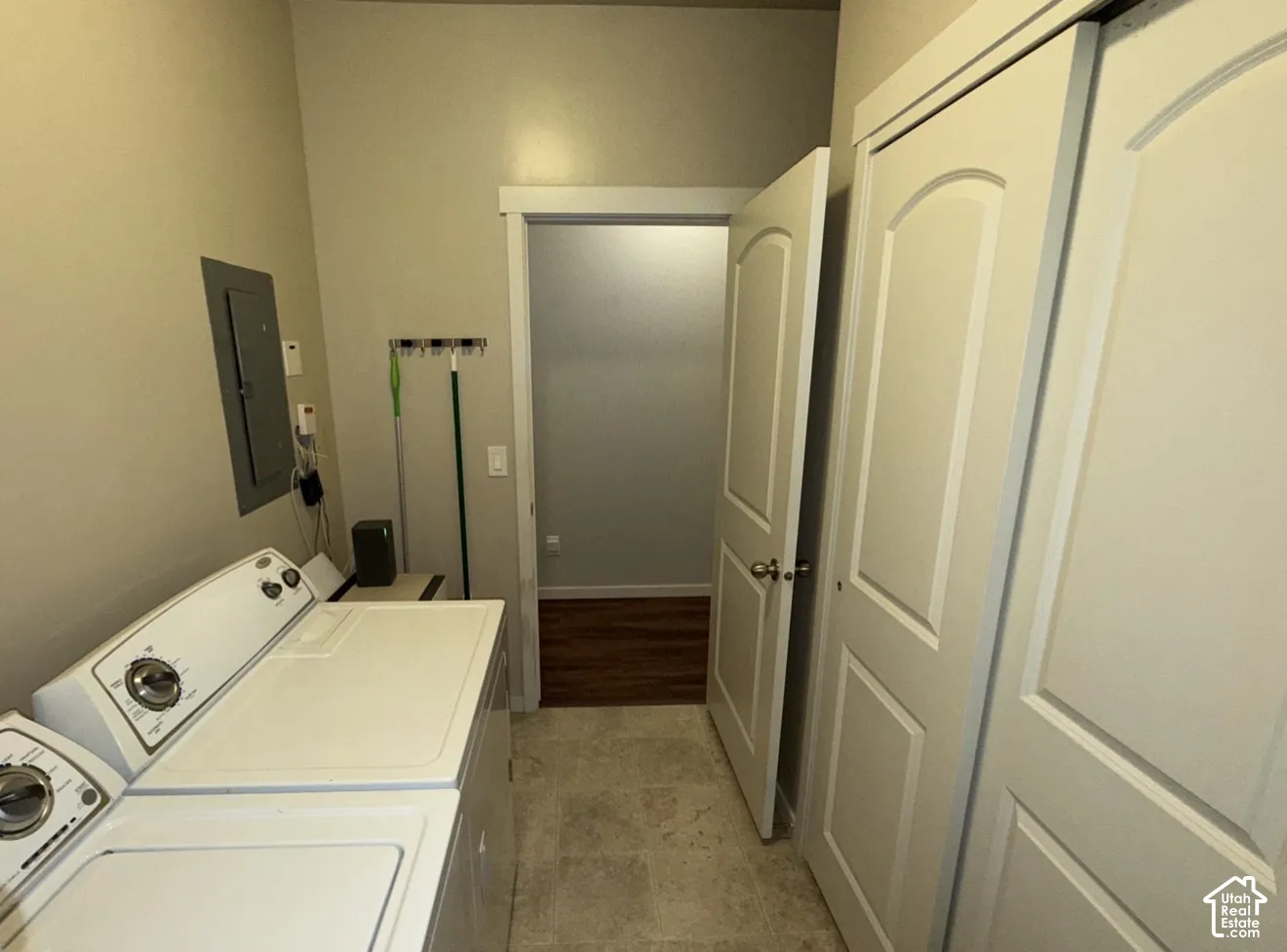 Utility room featuring tile flooring, sliding closet doors with recessed panels, and a mounted electrical panel