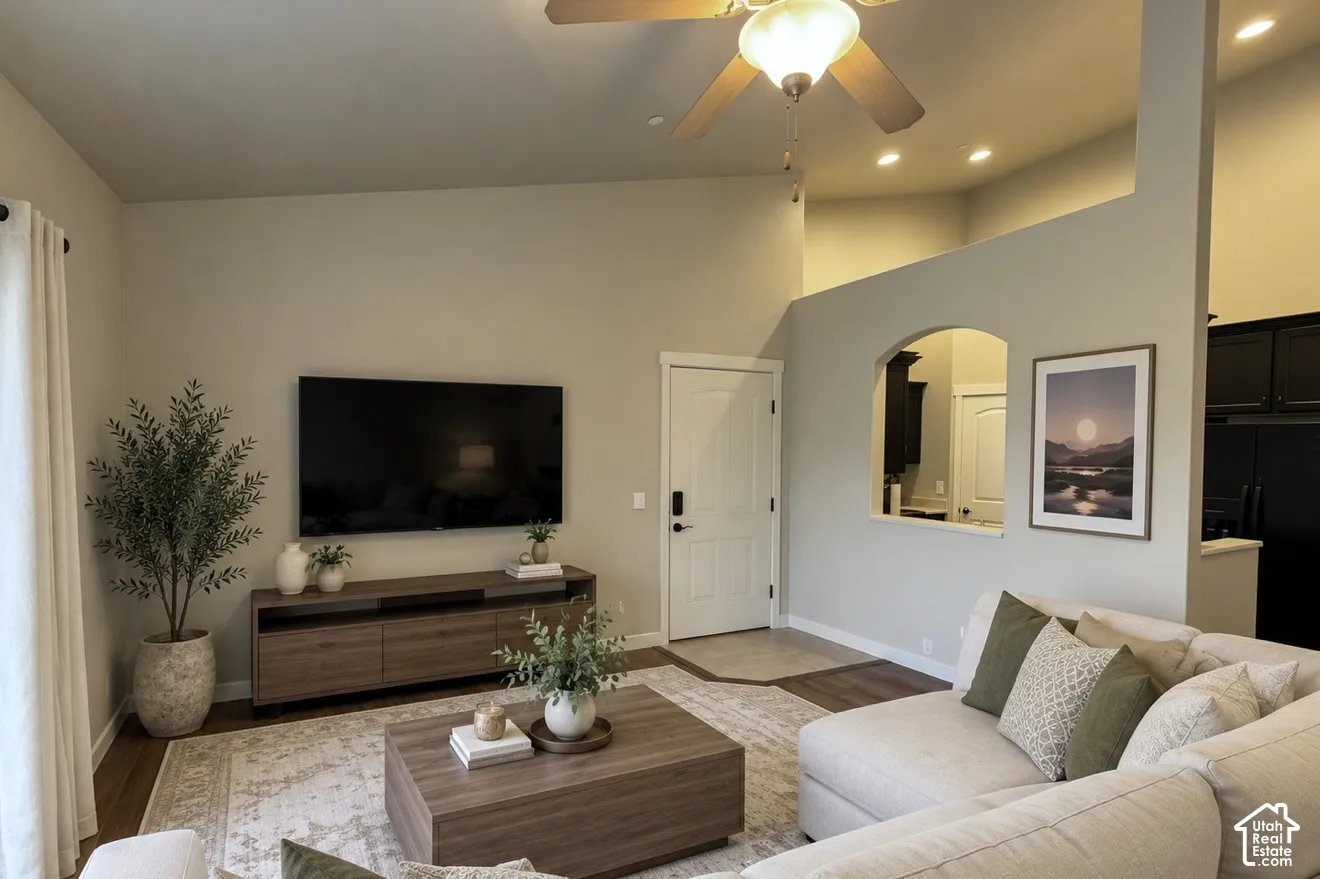 Vaulted ceilings, recessed lighting, archway architectural detail, and wood-finish flooring