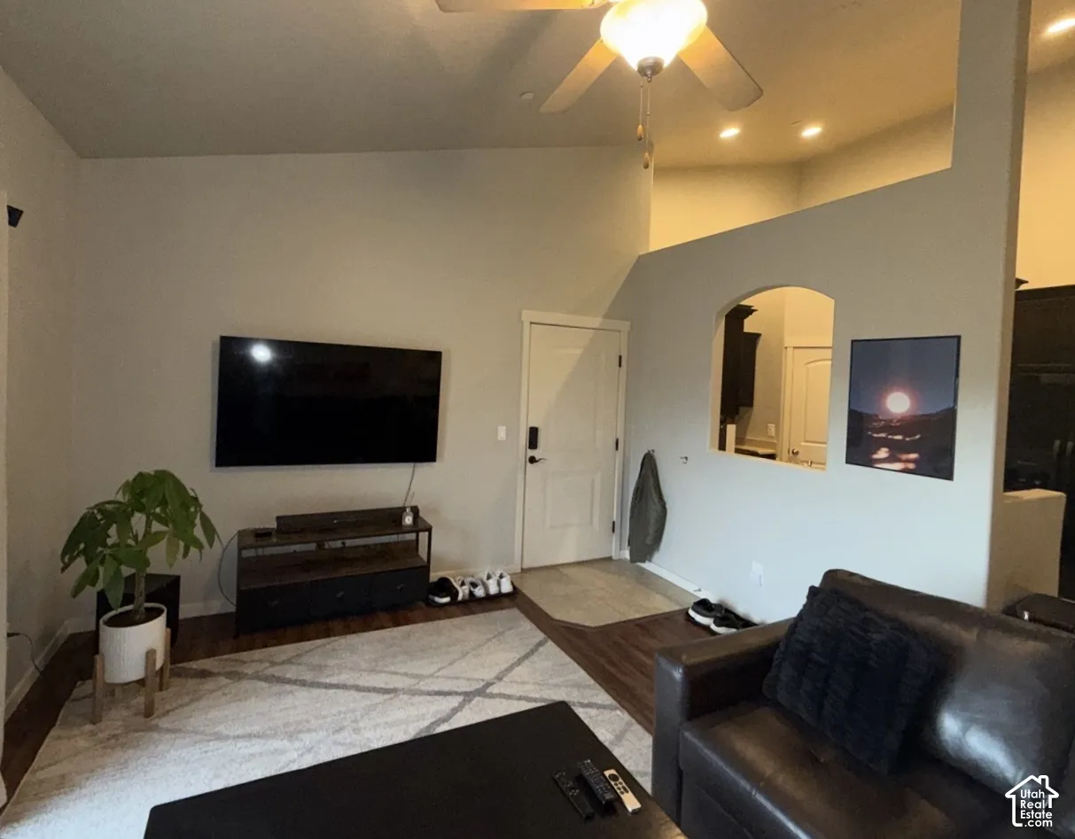 Vaulted ceilings, wood-finish flooring, recessed lighting, ceiling fan with integrated light fixture, and arched wall pass-through