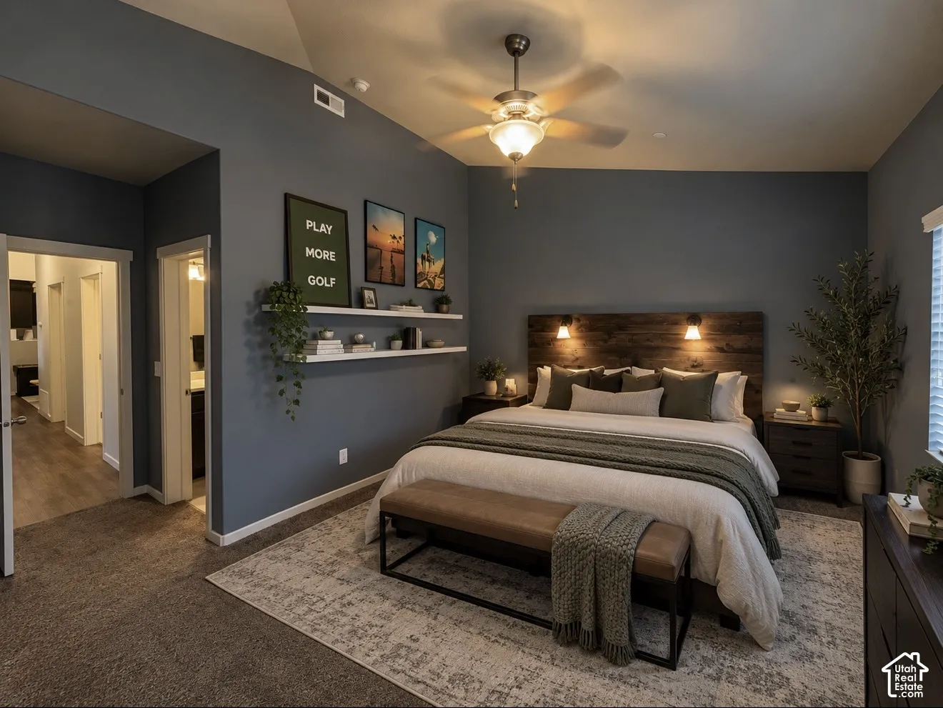 Vaulted ceilings with a central ceiling fan, built-in dual shelving, and a custom wood-panel accent wall featuring integrated wall-mounted lighting