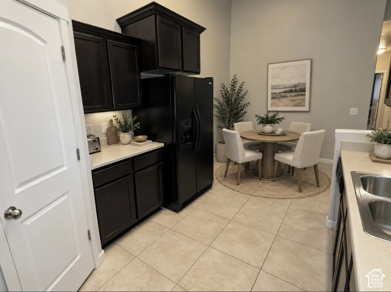 Kitchen area featuring dark-stained cabinetry, light-toned solid surface countertops, ceramic tile flooring, and high ceilings