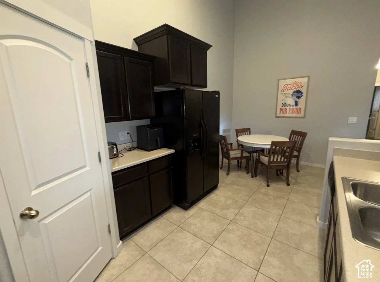 Dark-toned cabinetry, light-colored countertops, tiled flooring, high ceilings, and double-bowl stainless steel kitchen sink