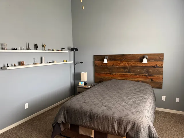 Bedroom with a paneled wood-finish headboard featuring two attached sconce lights