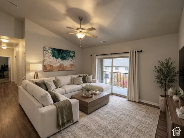 Living area featuring vaulted ceilings, wood-finish flooring, a ceiling fan with integrated lighting, and sliding glass doors to an exterior balcony