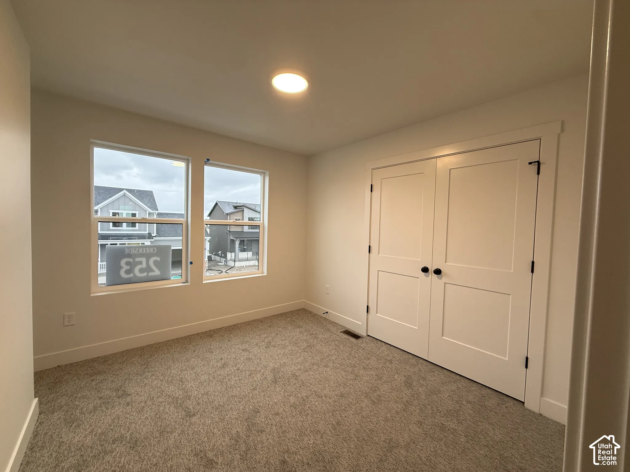 Warm neutral carpeting, white trim, recessed lighting, and two panel doors with matte black hardware