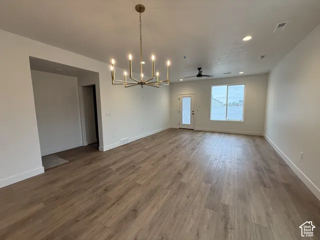 Spacious room featuring wood-finish flooring, a modern chandelier, recessed lighting, a ceiling fan, and access to an exterior door