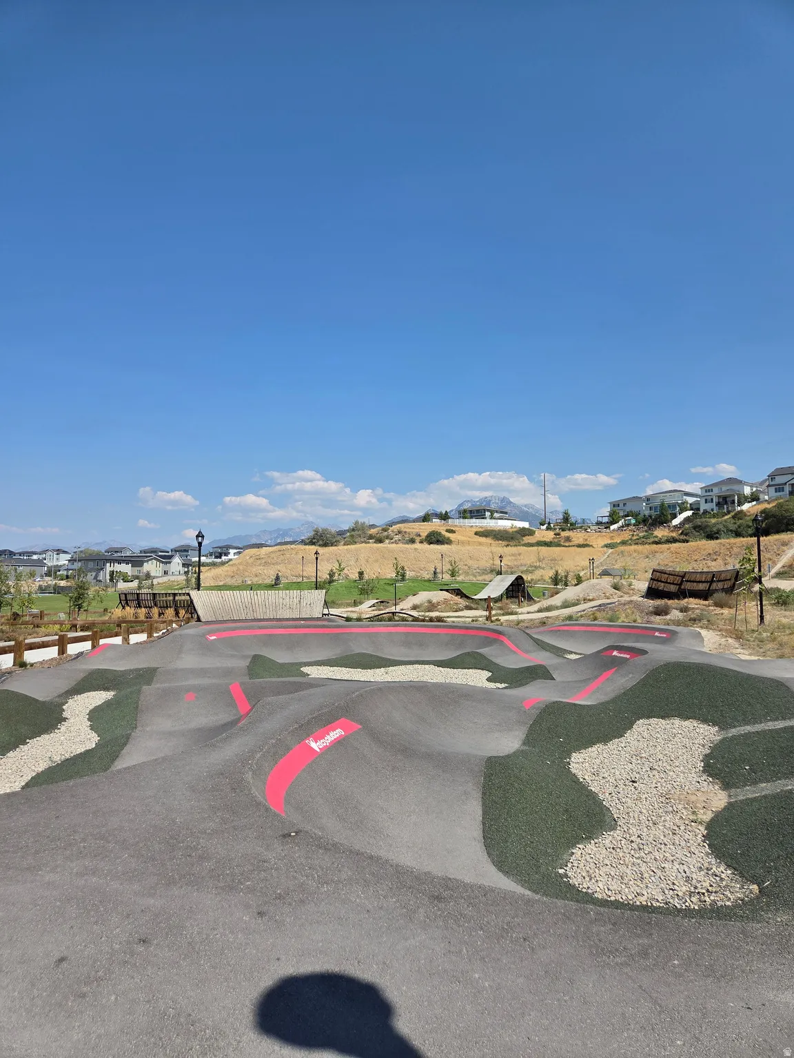 Outdoor pump track featuring asphalt and gravel surfaces with crimson accents