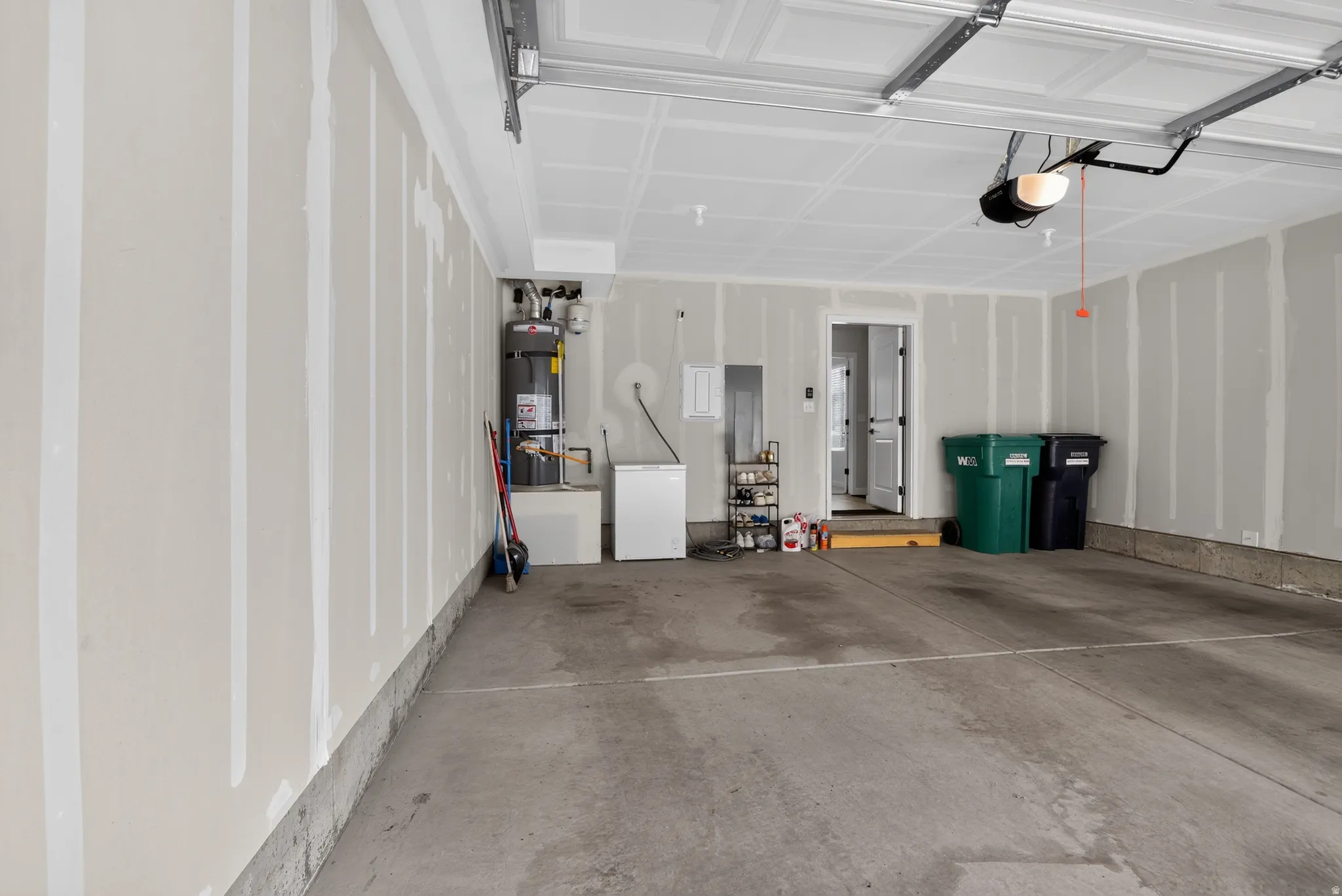 Spacious garage featuring a concrete floor, painted drywall, overhead garage door with opener, and utility access